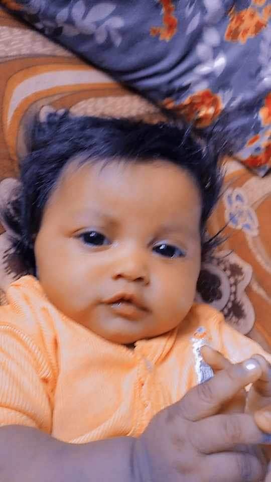 A baby wearing a pale orange jumpsuit