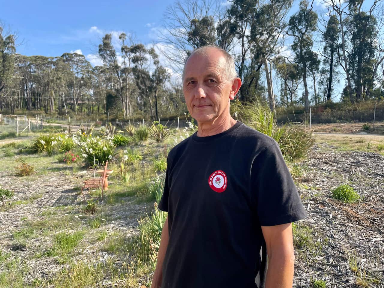 A man standing with a garden behind him.