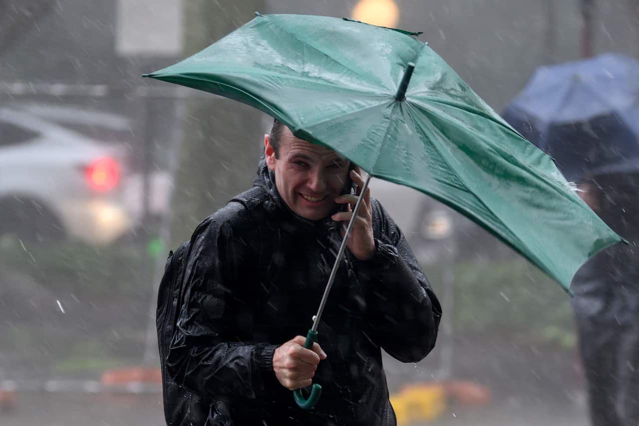 A man in the rain holding a green umbrella