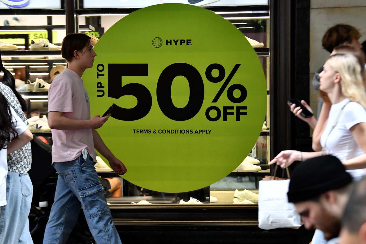 People go past a window of a shop.