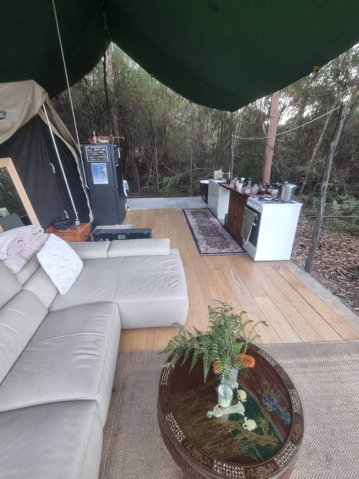 An outdoor tent setup with a kitchen and lounge. 