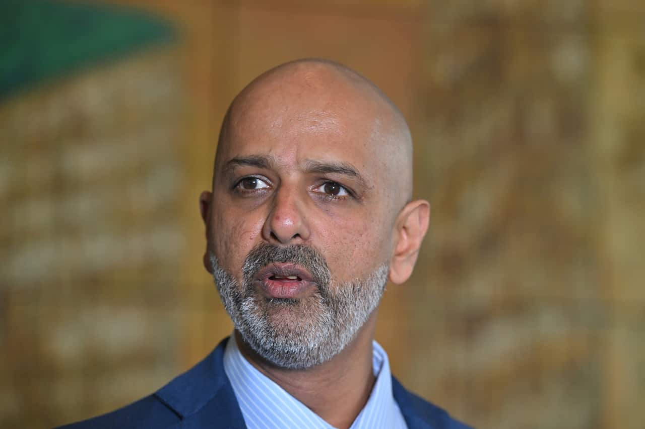A man standing in a hallway, with a serious look on his face.