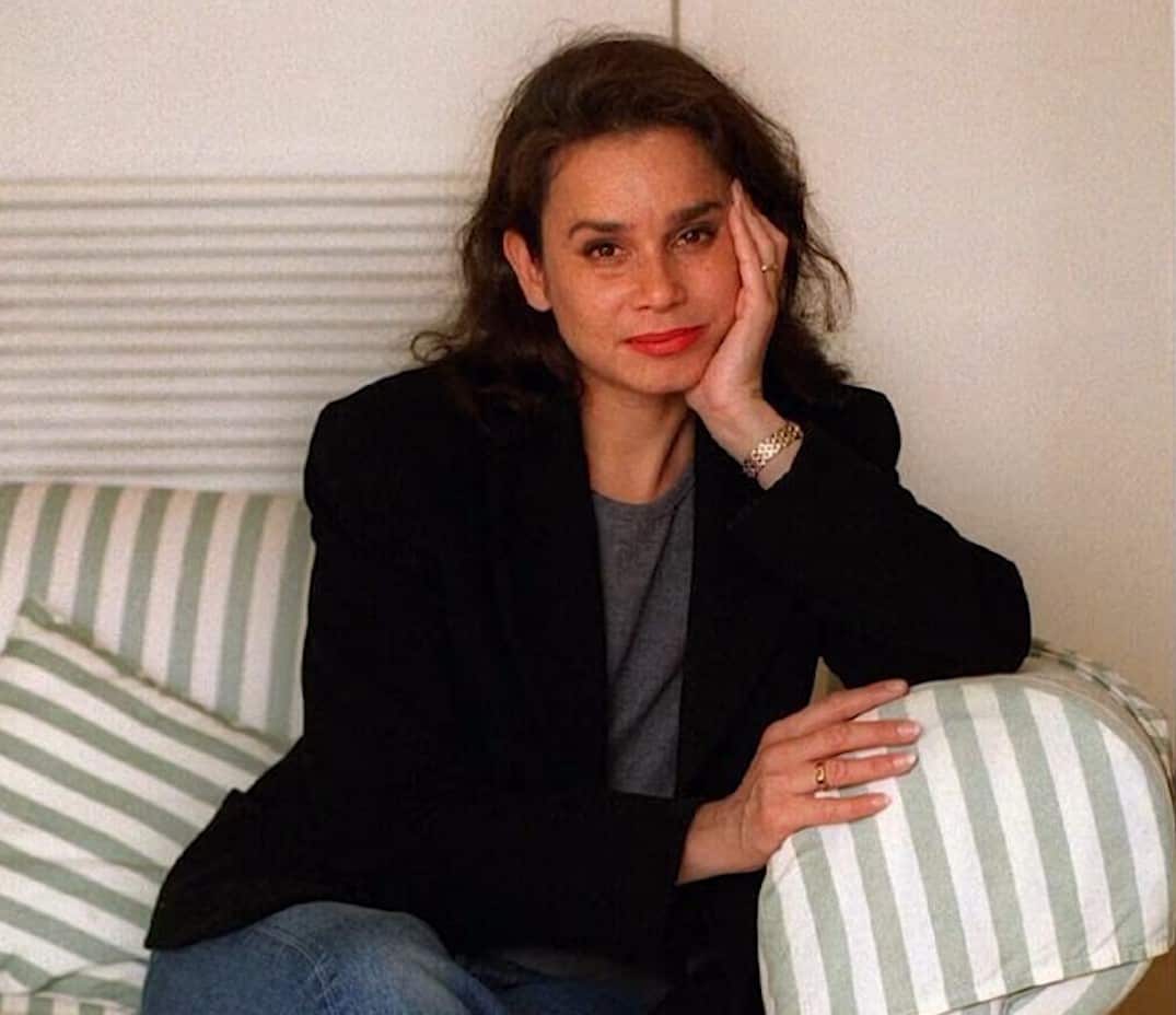 A woman posing for a photo while seated on a couch.