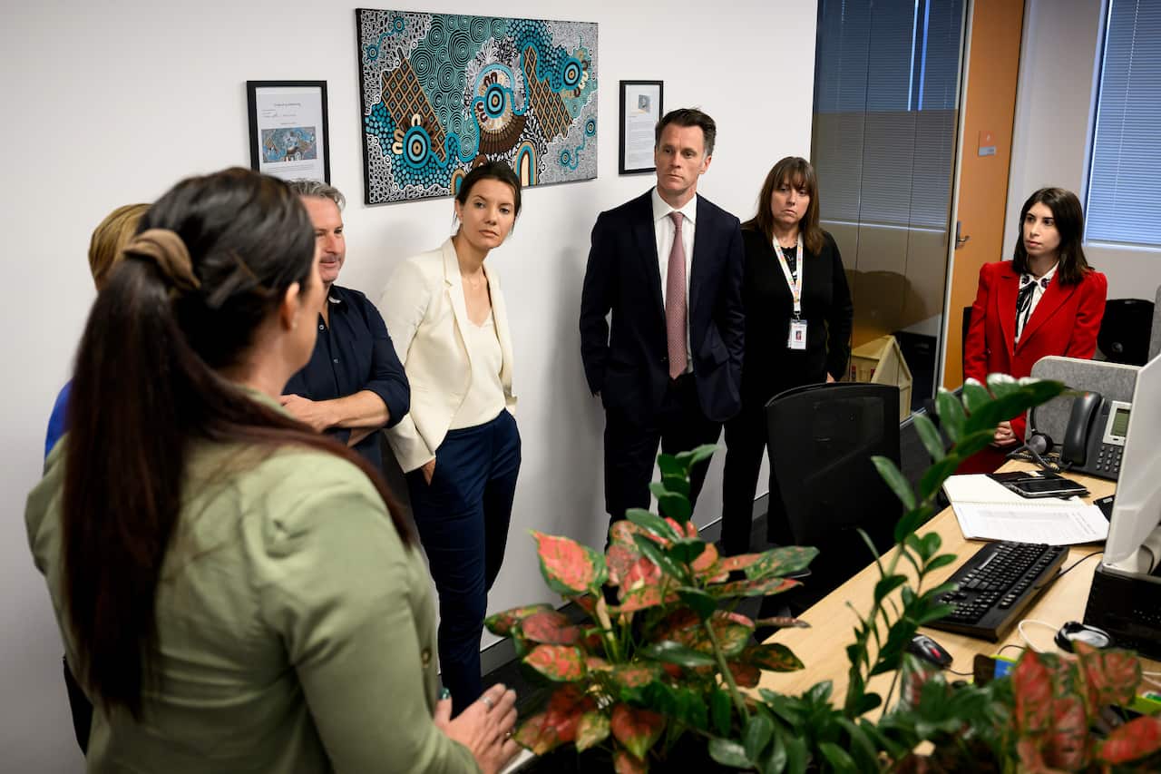 A group of people standing near each other in an office. One of them is speaking.