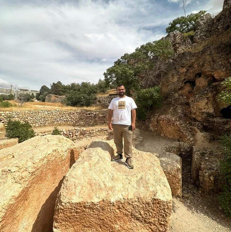 A man standing on a large rock outside.