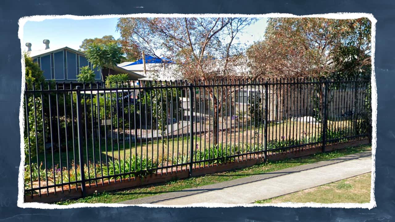 An image taken from the edge of a street shows an outdoor fenced area at a school.