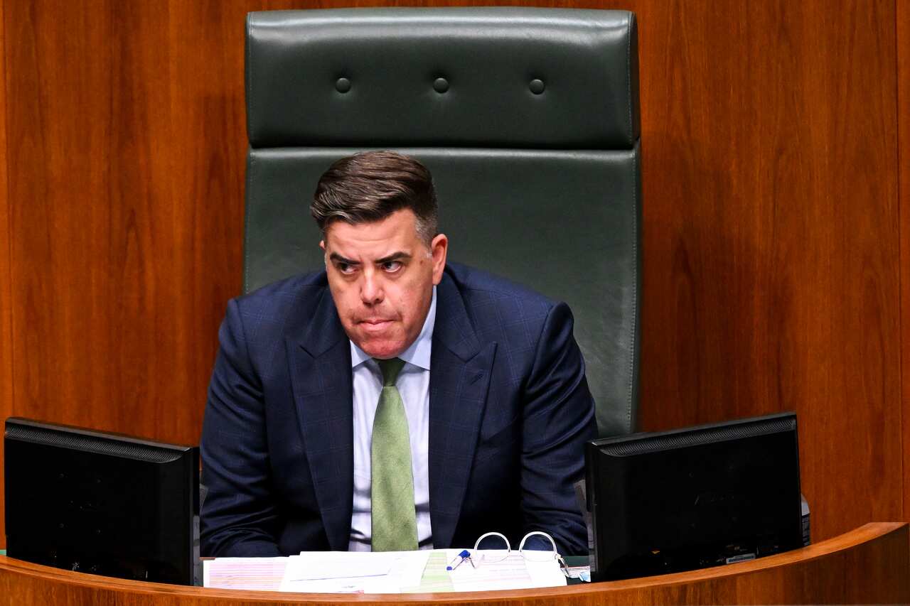 Man in suit sitting in the Speaker's chair.