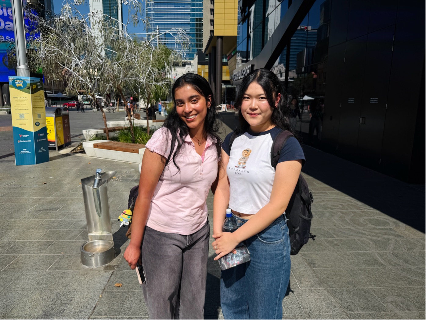 Two young girls posing for a photo on a street.
