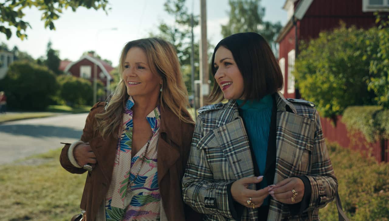 Two smiling women walk down a suburban street.