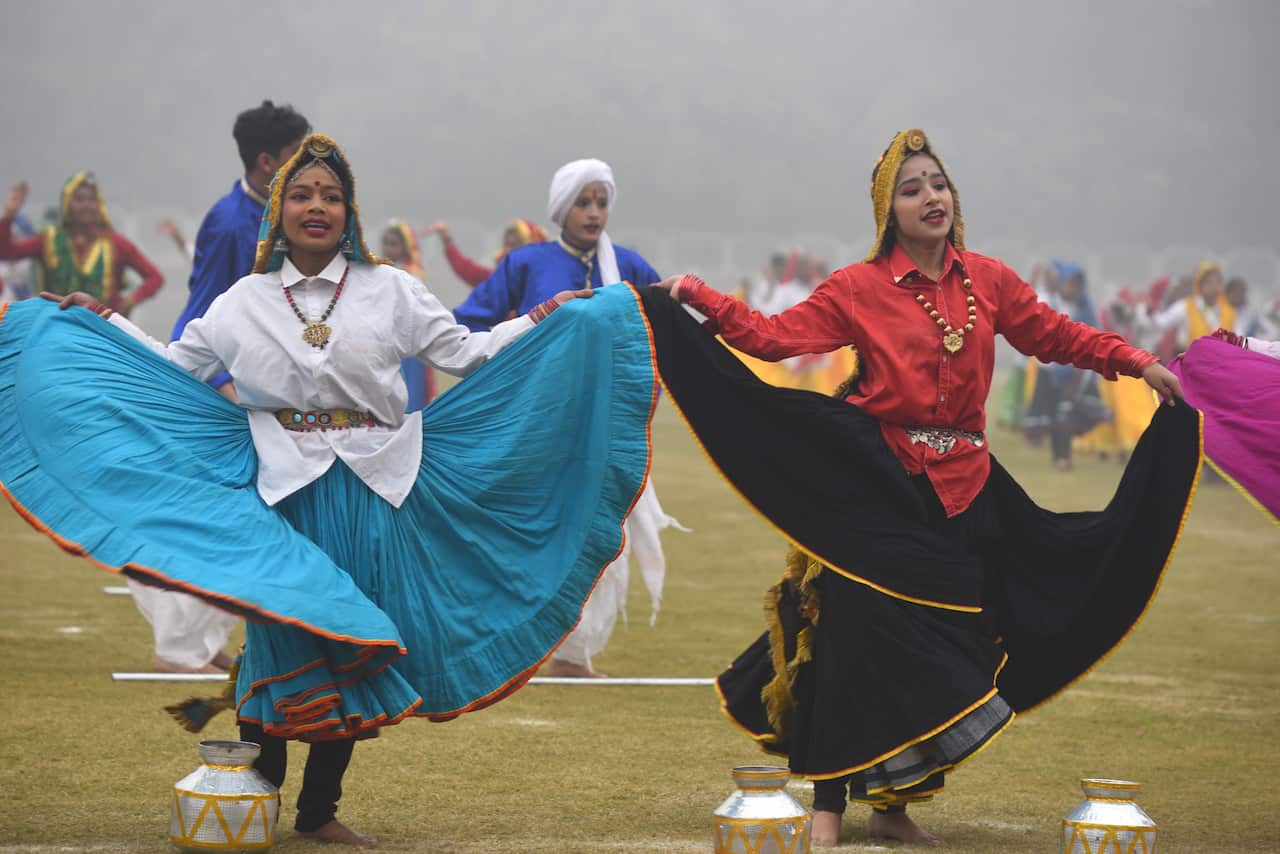 Women in long flowing skirts dance during a parade rehearsal. 
