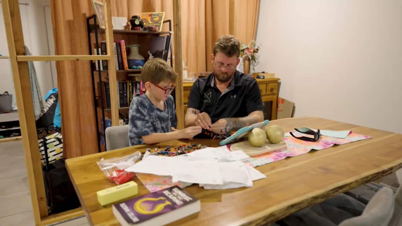 a man and a young boy working on craft at a table