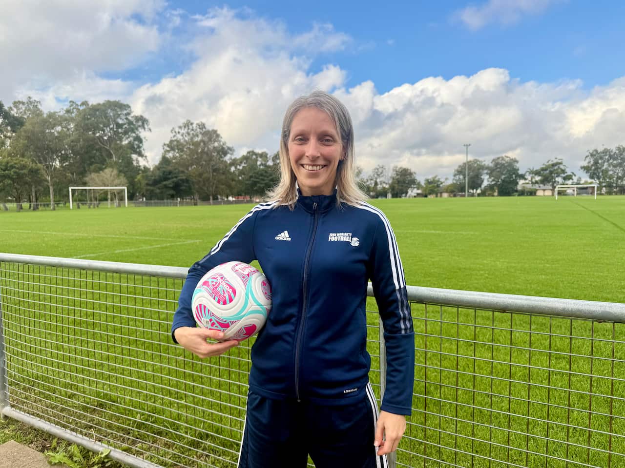 A woman with blonde hair holding a football.