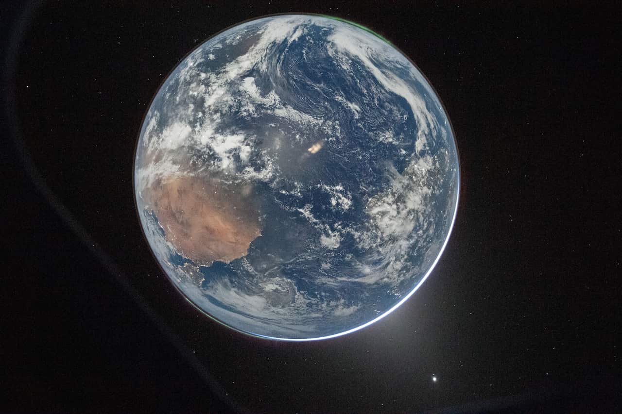 A photograph of Earth taken from space, showing clouds covering an ocean and a continental landmass