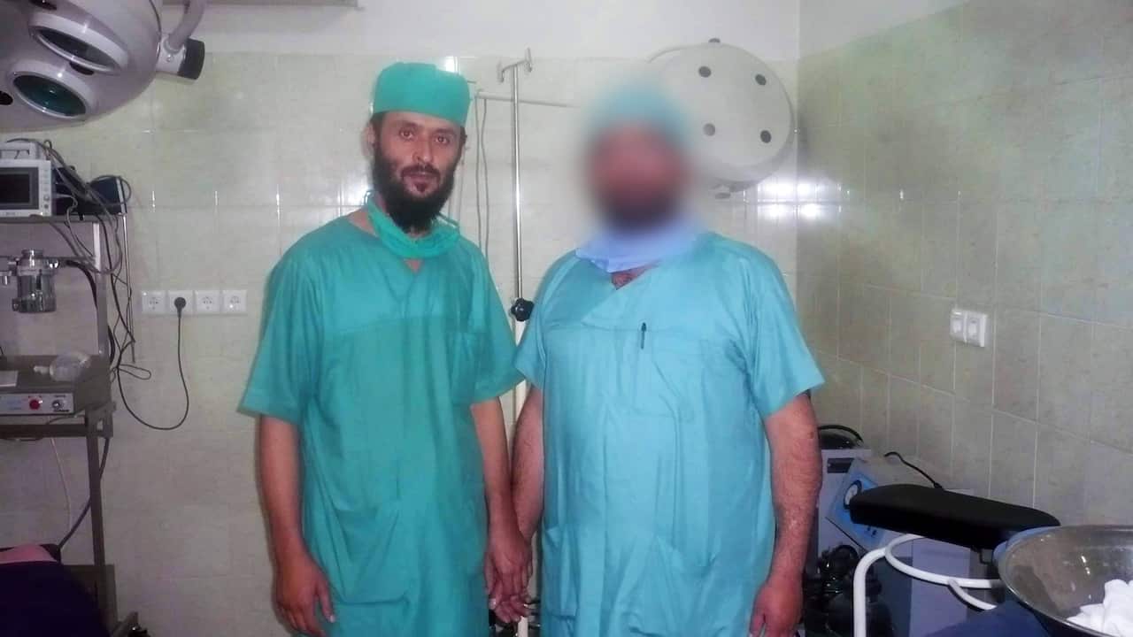 Two men, one face blurred standing in surgery room with uniforms