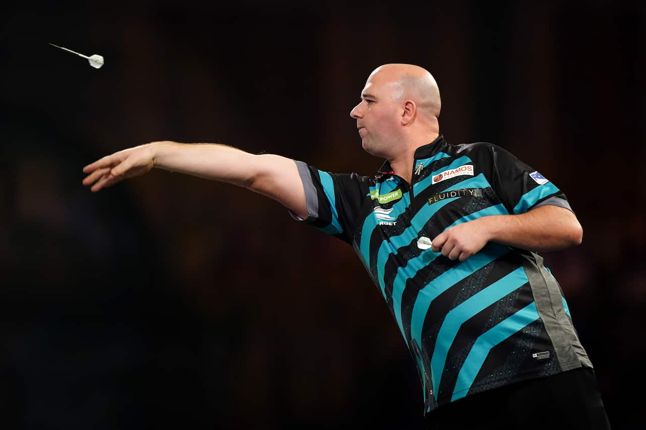 A bald-headed man in a striped T-shirt throws a dart.