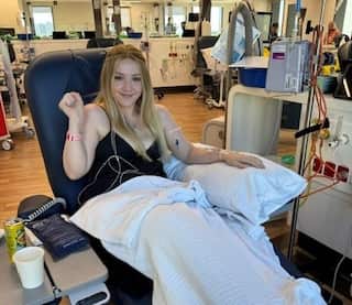 A blonde woman sitting in a chair in a hospital.