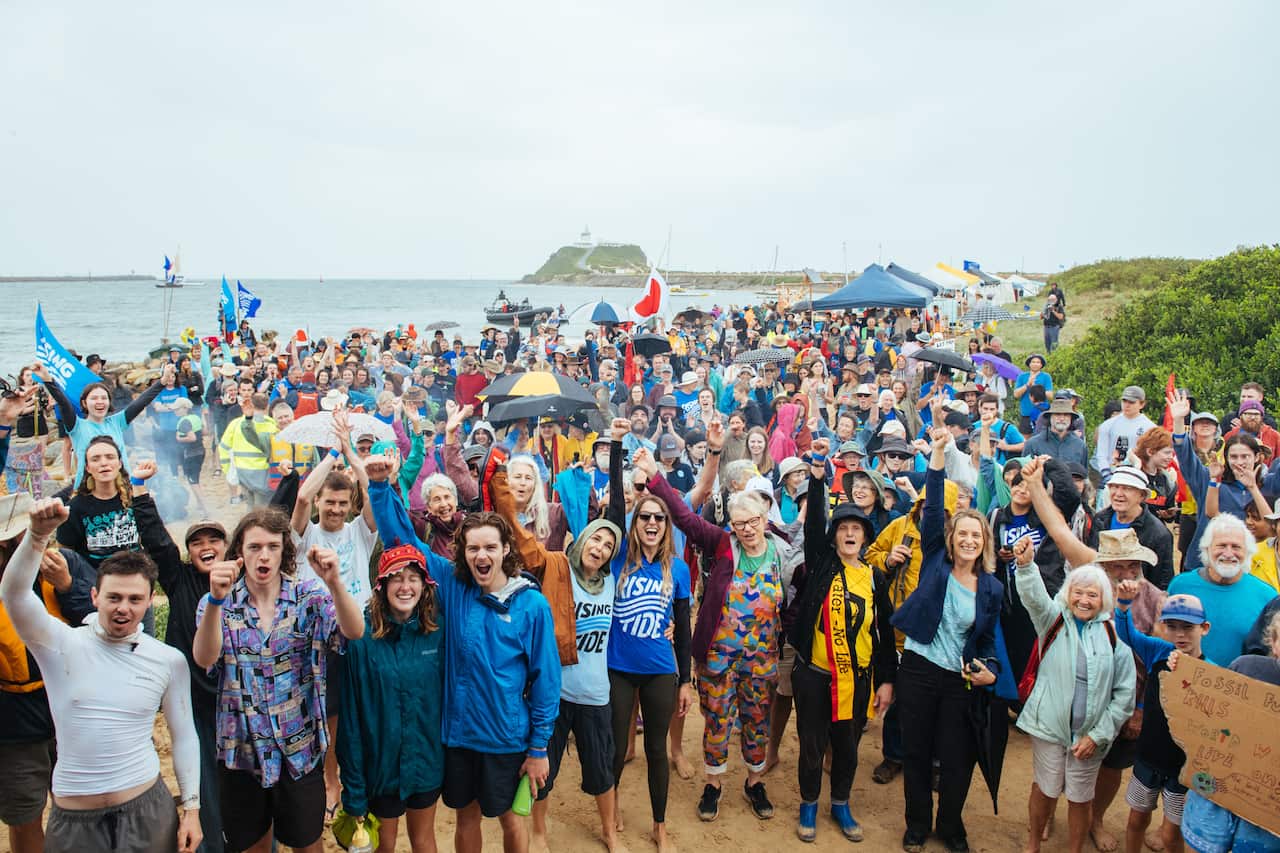 A large group of people on a beach holding fists in the air.