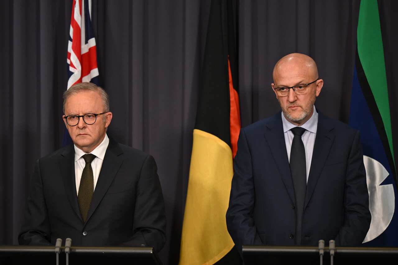 Anthony Albanese and Mike Burgess standing in front of a blue curtain, and Australian, Aboriginal and Torres Strait Islander flags.