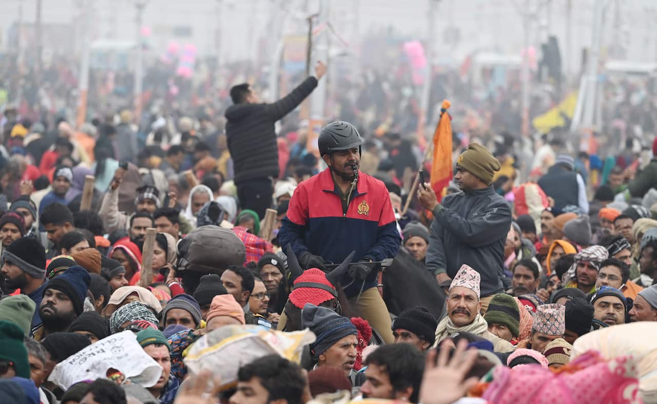 A police officer on a horse makes his way through a massive crowd.