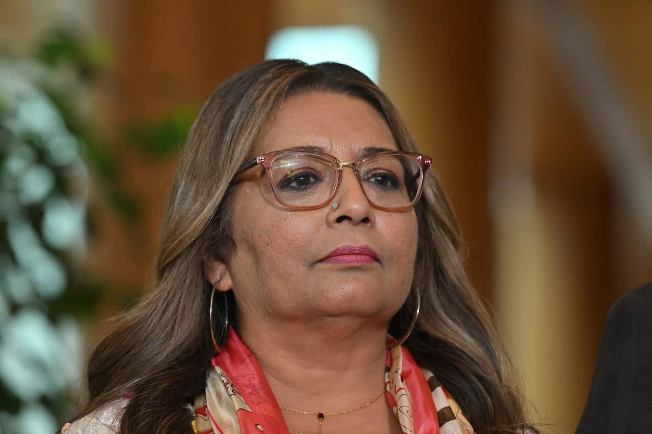 Woman with nose piercing and hooped earrings.