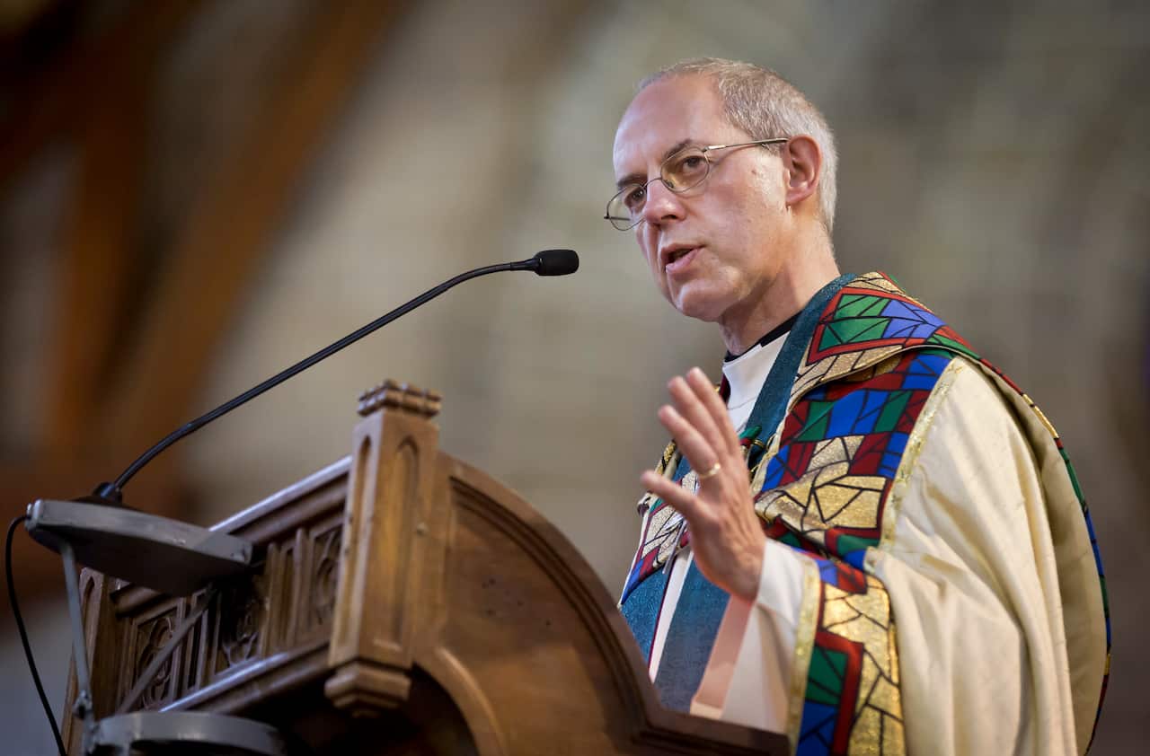 A man in a bishop's gown speaking into a microphone at a lectern.
