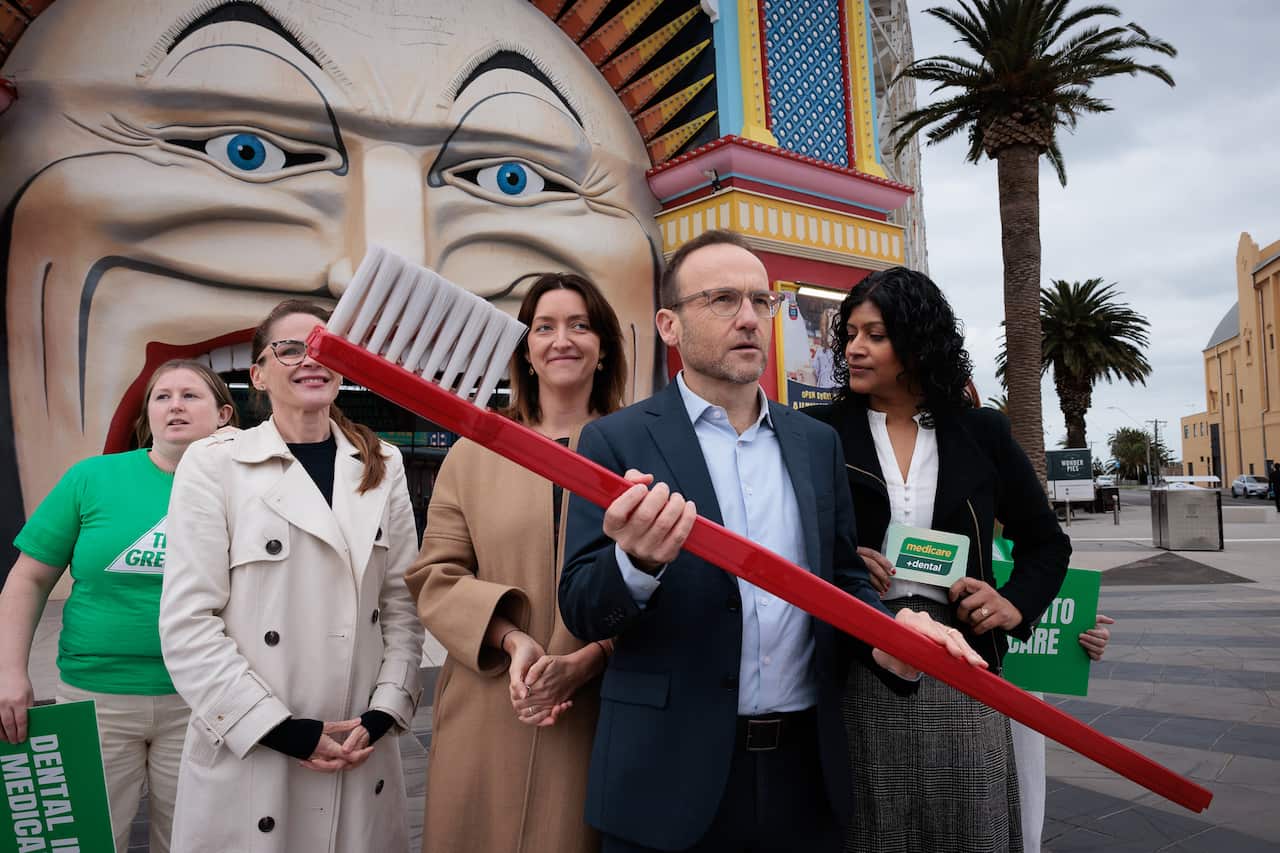 Man holding a large, red toothbrush. 