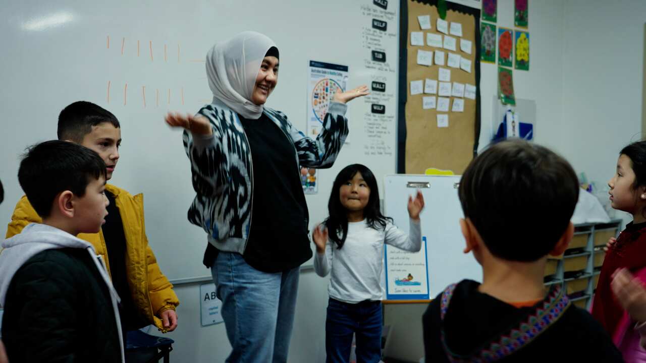 A teacher stands in a cirlce with her students.