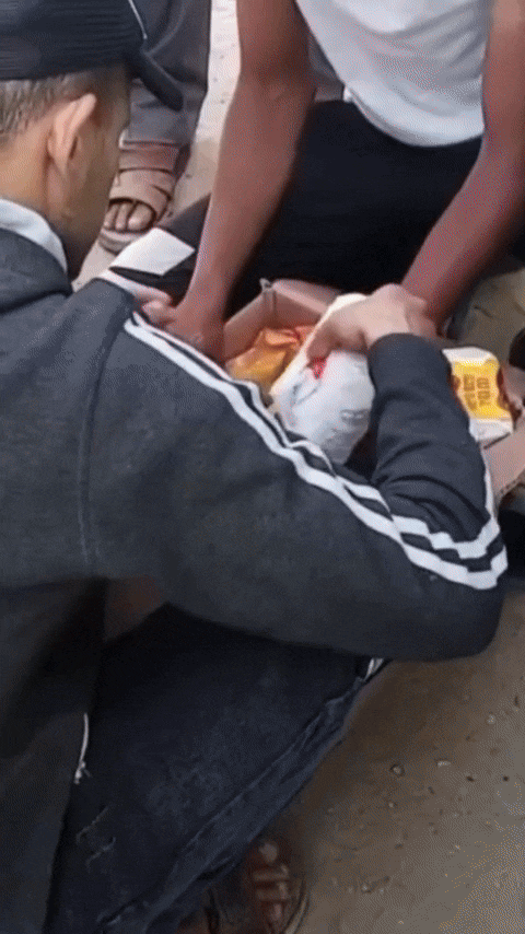 People sort through a box of food supplies.