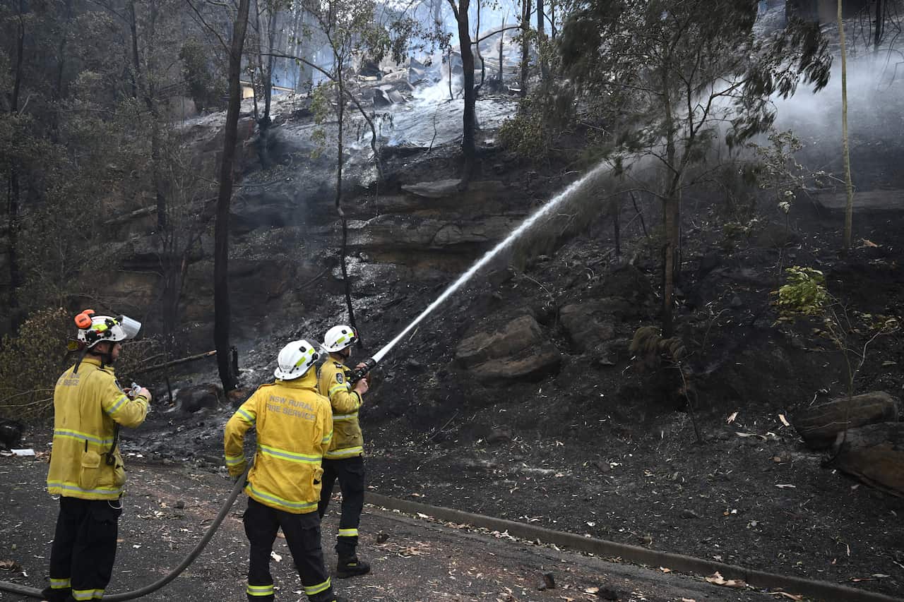 Firefighters holding a hose and putting out a fire.