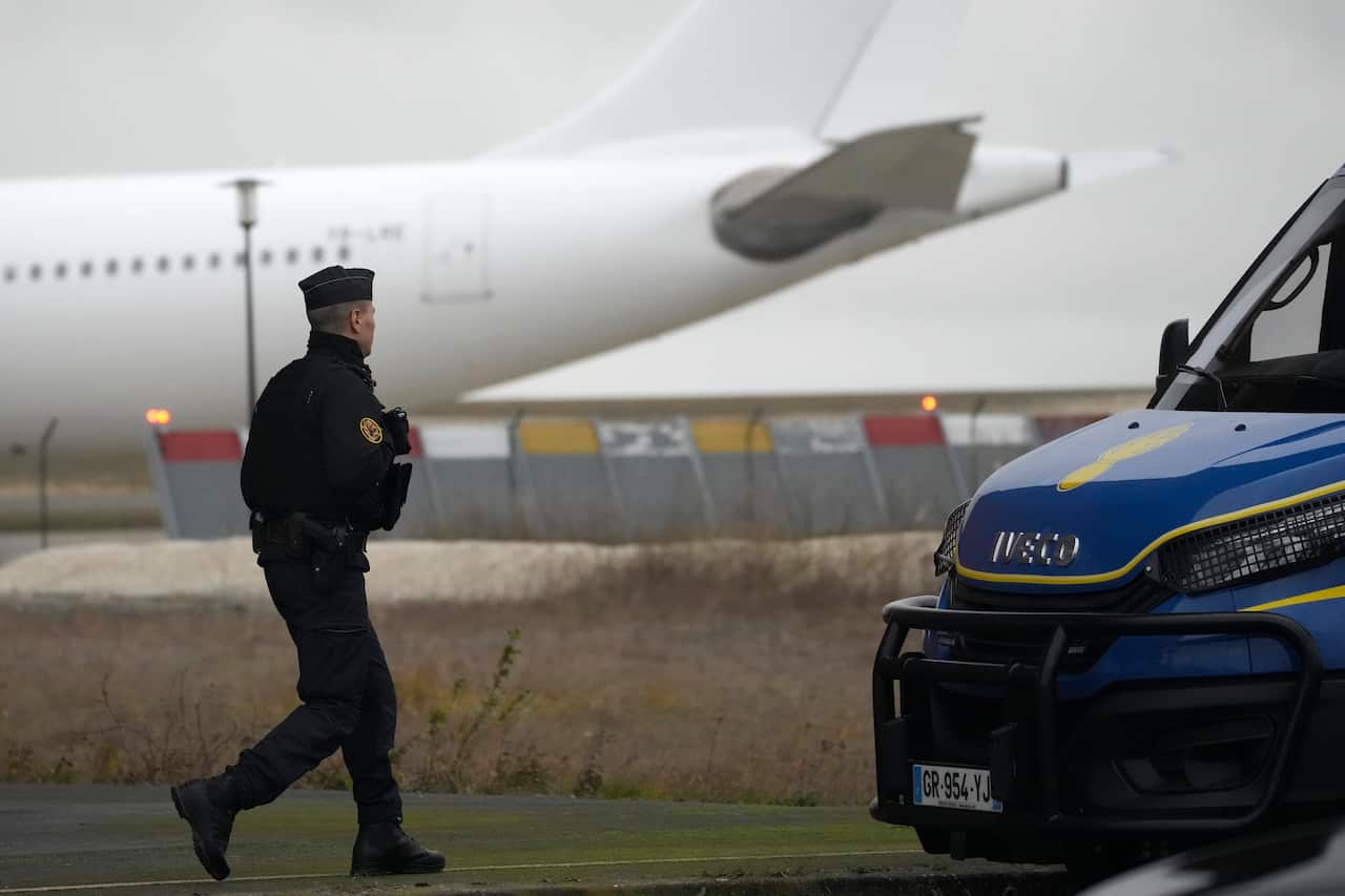 A Gendarme walks in front a plane