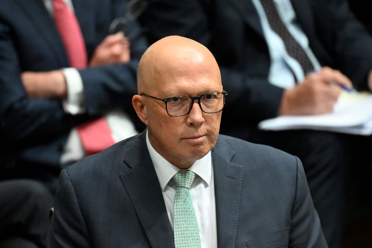 A man wearing a suit and a tie looks on.