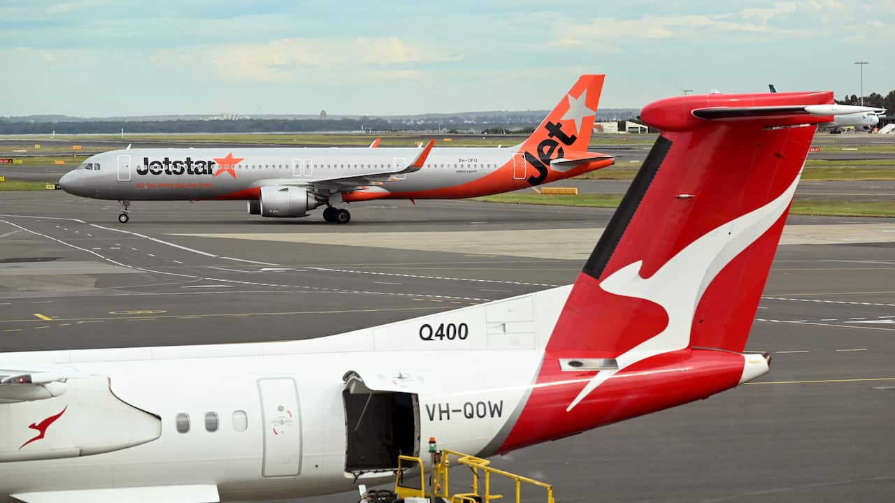 A Qantas plane at an airport with a Jetstar plane in the background.