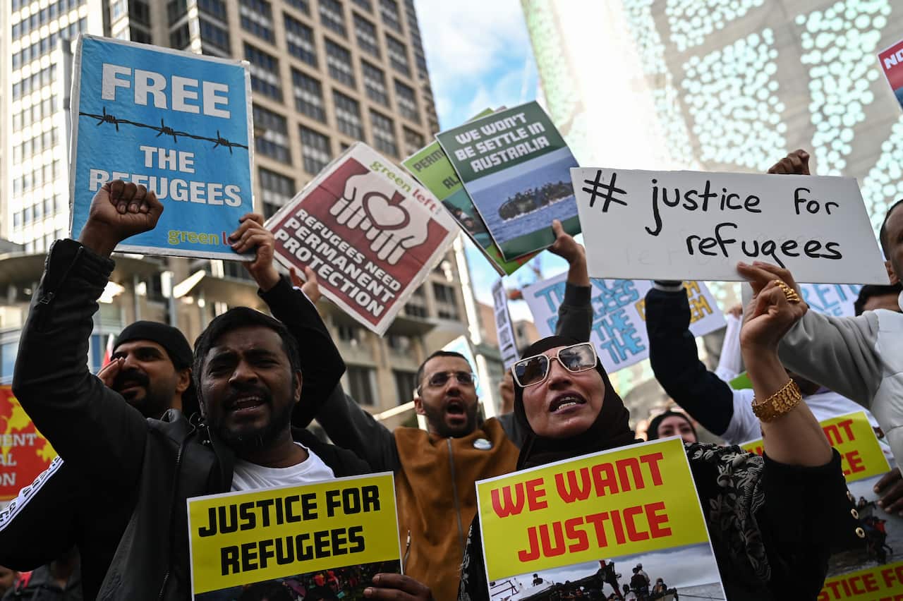 A group of protesters hold placards during a rally for refugee rights.
