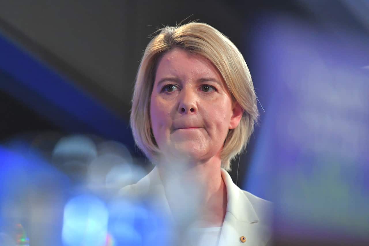 A woman with short blonde hair and a white blazer.