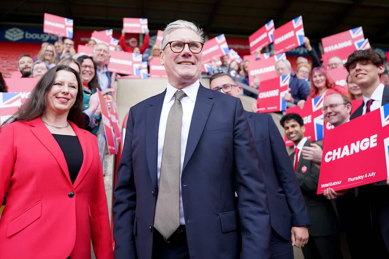 UK Labour leader Keir Starmer stands with supporters holding "Change" signs after the party won the 2024 election.