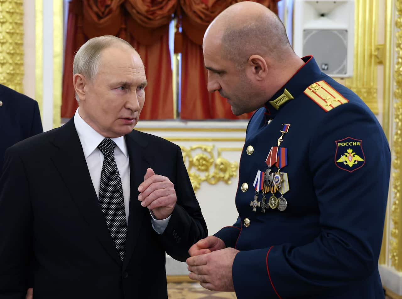 Two men in the official suits: Russia's president Vladimir Putin and the soldier