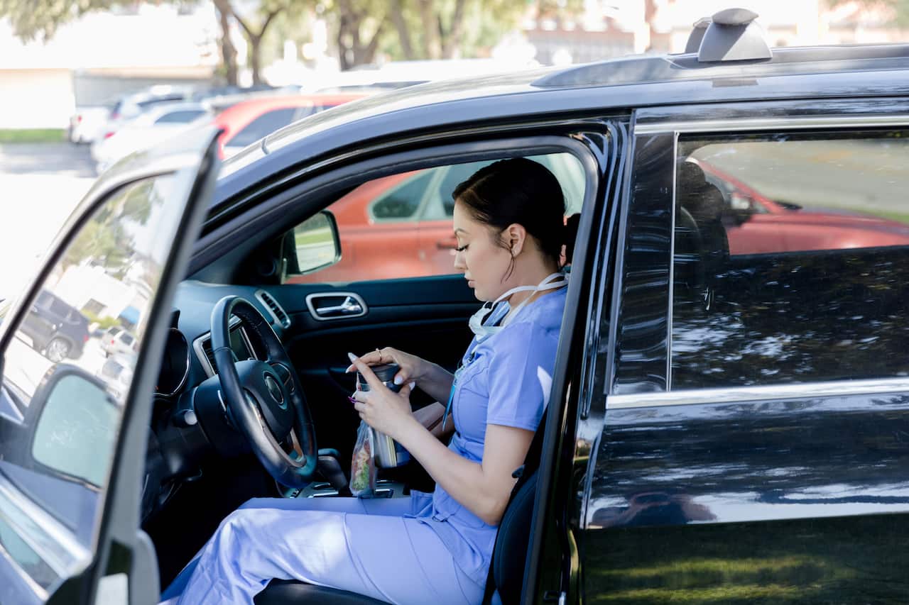 Female healthcare worker arrives in car with lunch and coffee