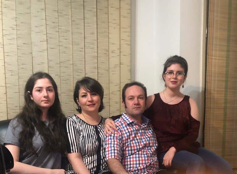 Three women and a man sitting together posing for a photo inside