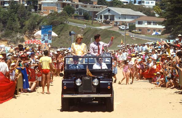 Charles and Diana stand in the back of a Land Rover jeep driving on Terrigal beach and wave to crowds.