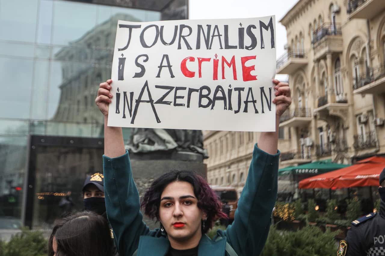 Person holds up sign that reads "Journalism is a crime in Azerbaijan"
