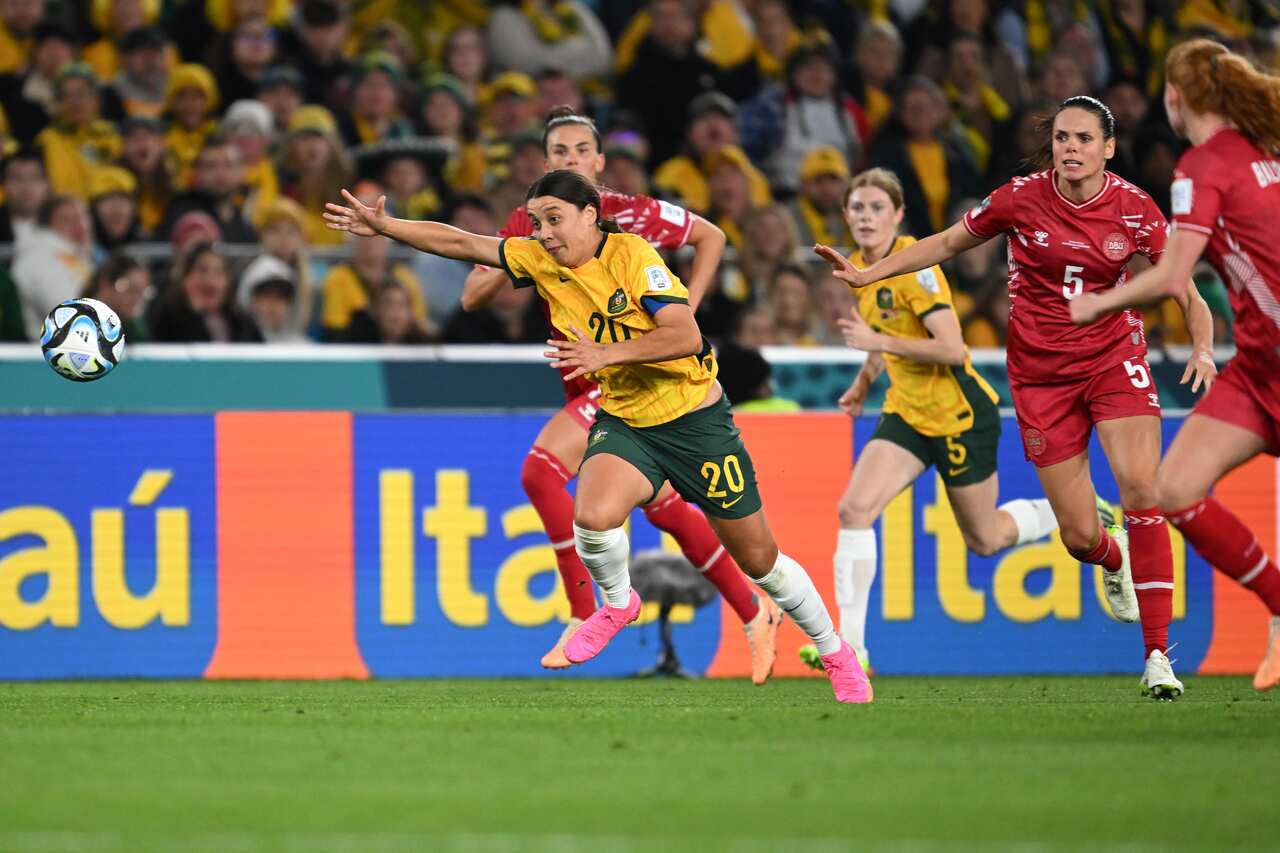 A football player in green and gold jersey chases down the ball.