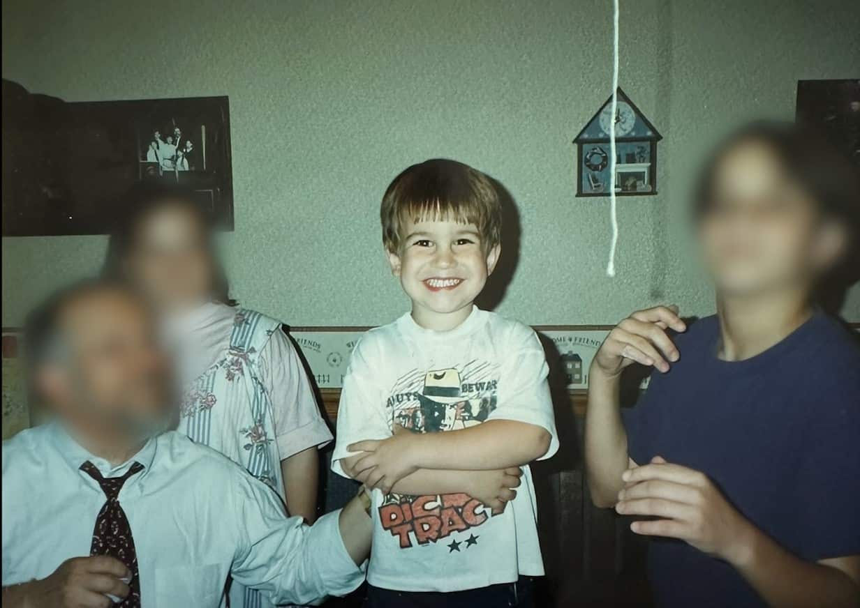 An image of a family with a young boy standing in the centre smiling 