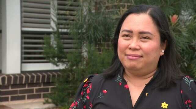 A woman in a floral dress in front of a brick house