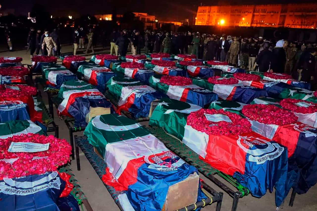 Lines of coffins lined up with Pakistani flags and wreaths. 