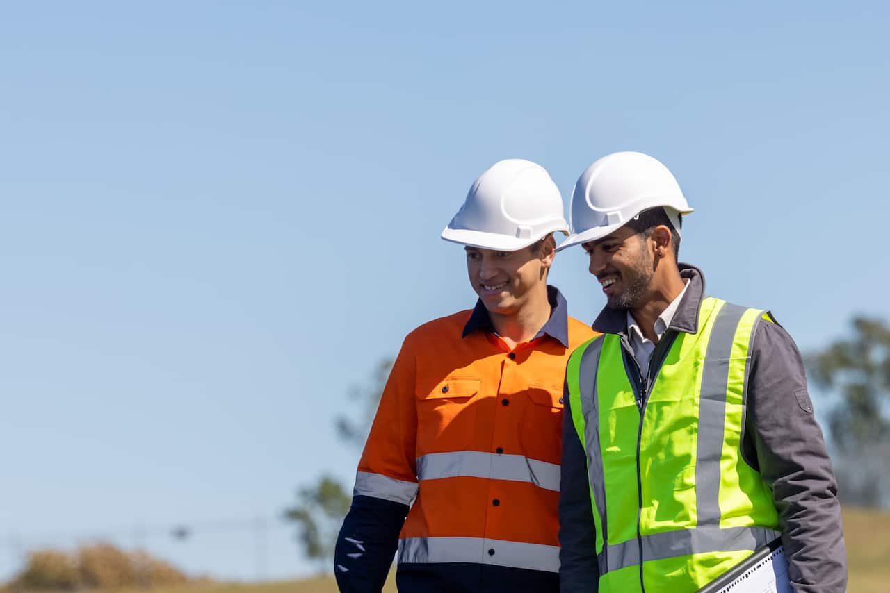 Engineer and Apprentice Working Together On Solar Farm Installation