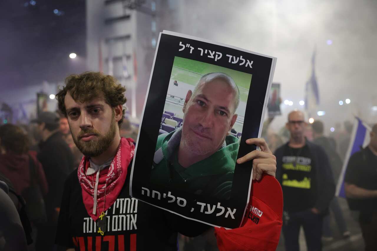 A man holds up a photo of a person who was taken hostage.
