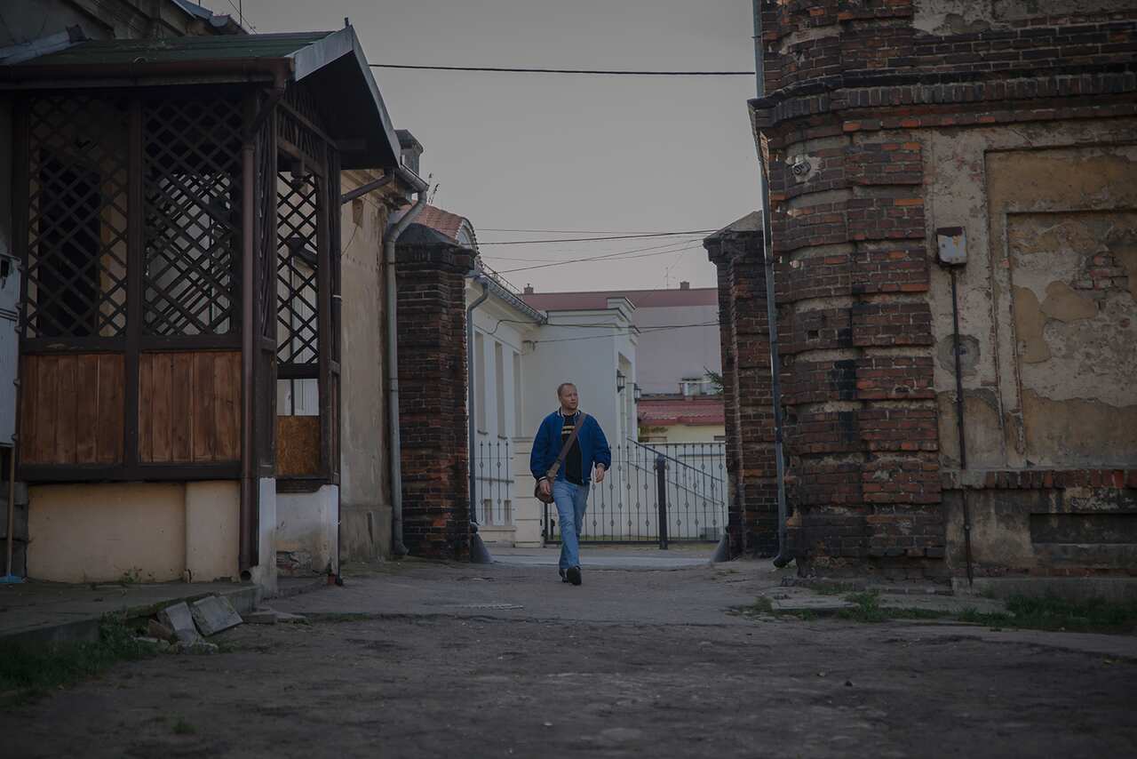 A man walks into a shadowed alleyway. 