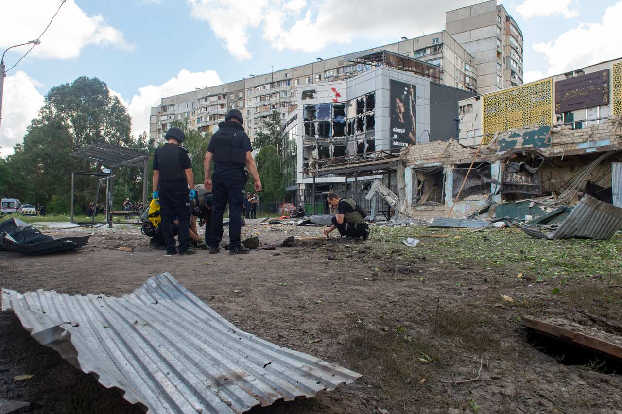Law enforcement officers examine the scene after Russian shelling destroyed buildings. 