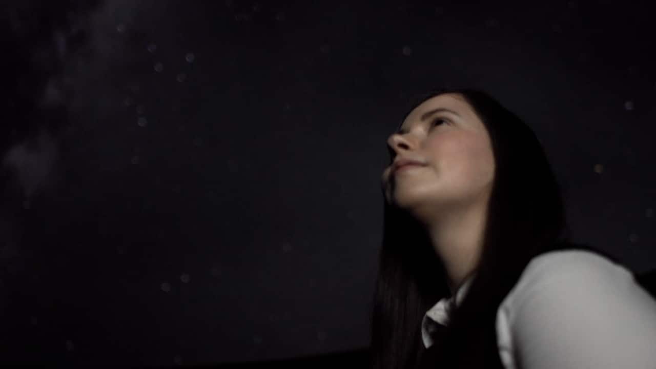 A woman stares into the night sky.