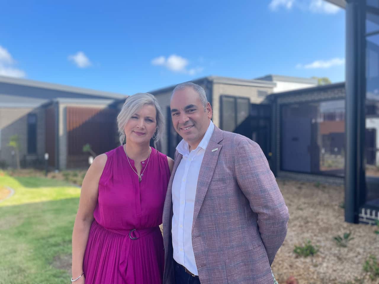 A man and a woman stand close tother outside for a photo.